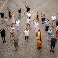Eine Rose als Dankeschön: Ensemblemitglieder und MitarbeiterInnen des Linzer Musiktheaters mit Bischof Manfred Scheuer, Schwester Maria Schlackl und ihrem Team (alle mit orangefarbenem Schal) im Innenhof des Linzer Bischofshofs.
